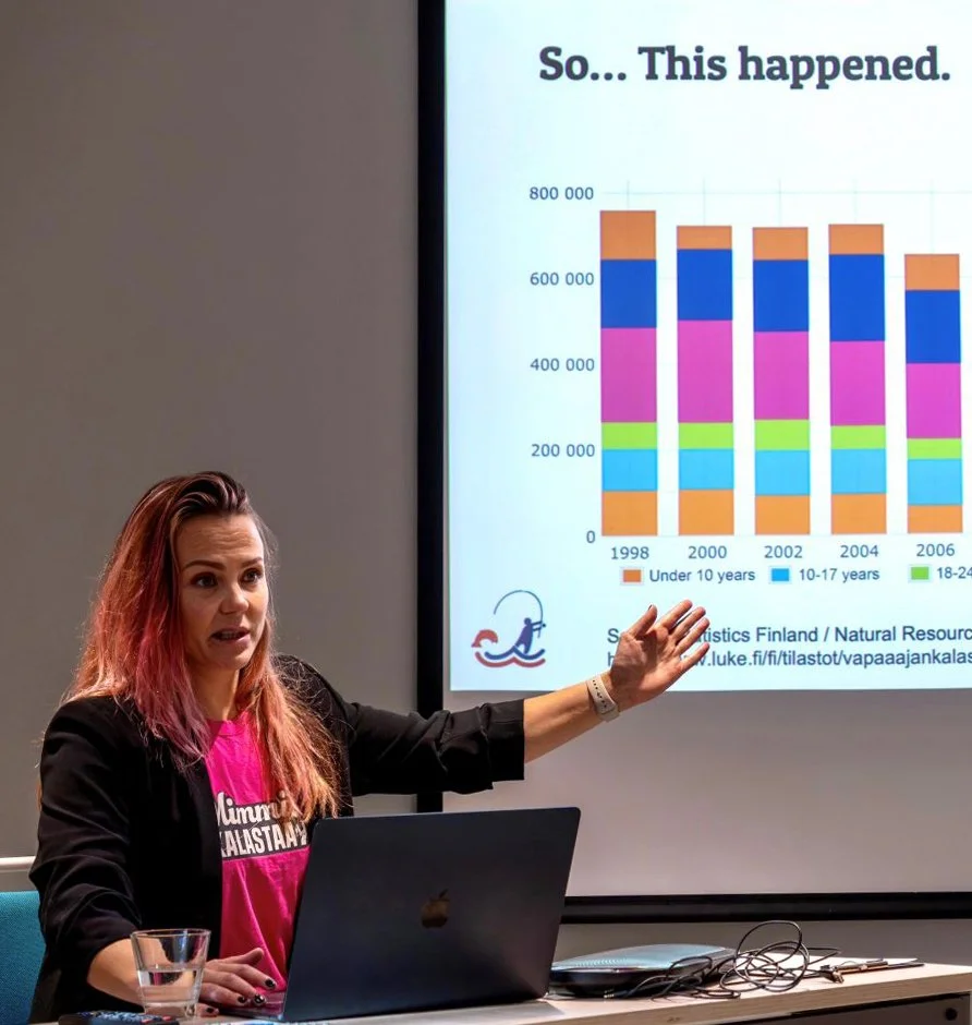 Nainen esittelee pylväsdiagrammia, jossa on eri ikäryhmien väestöntietoja vuosilta 1998-2006.