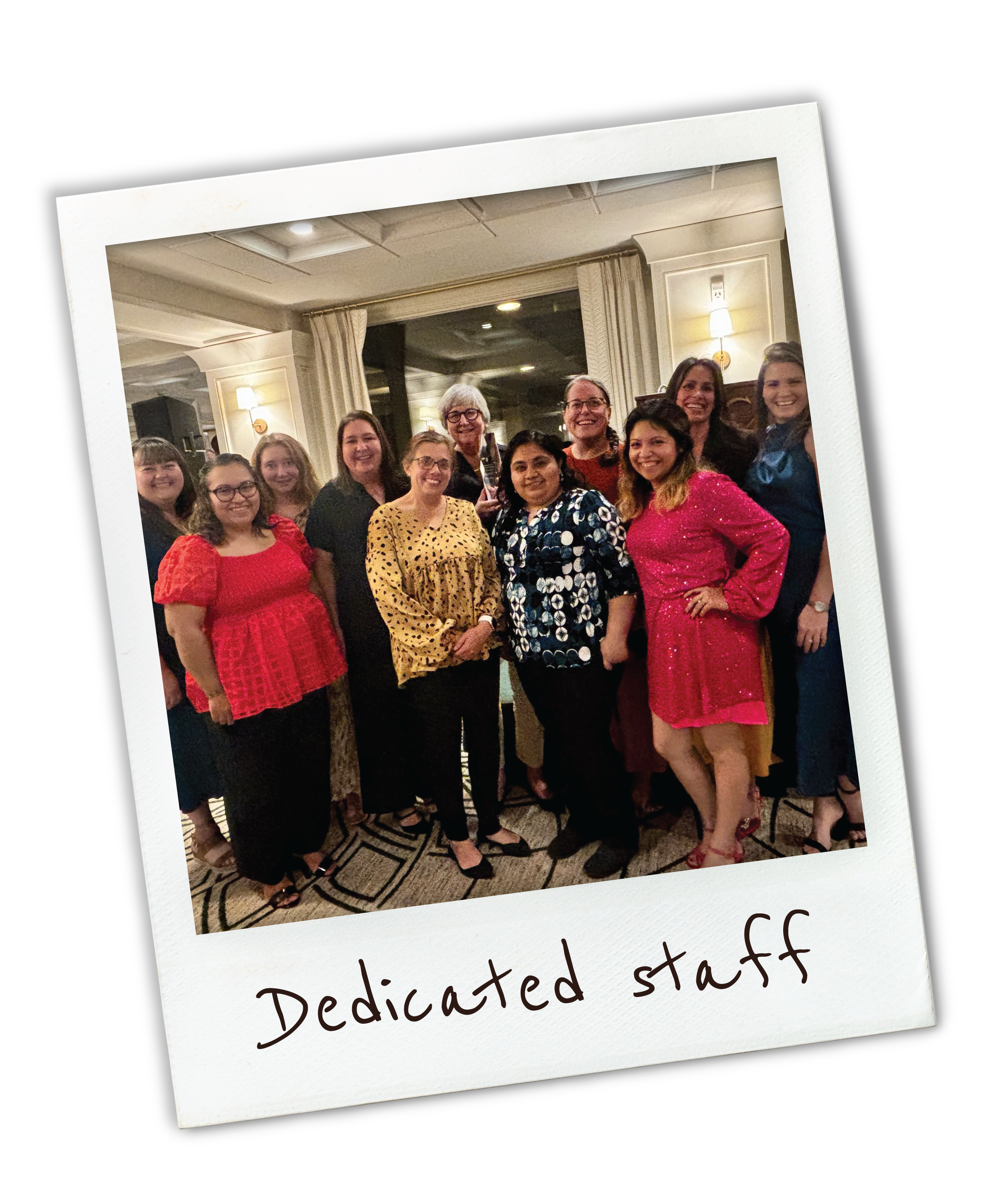 Group of women standing together at an indoor event, smiling, with the words "Dedicated staff" written on a white border at the bottom of the photo.