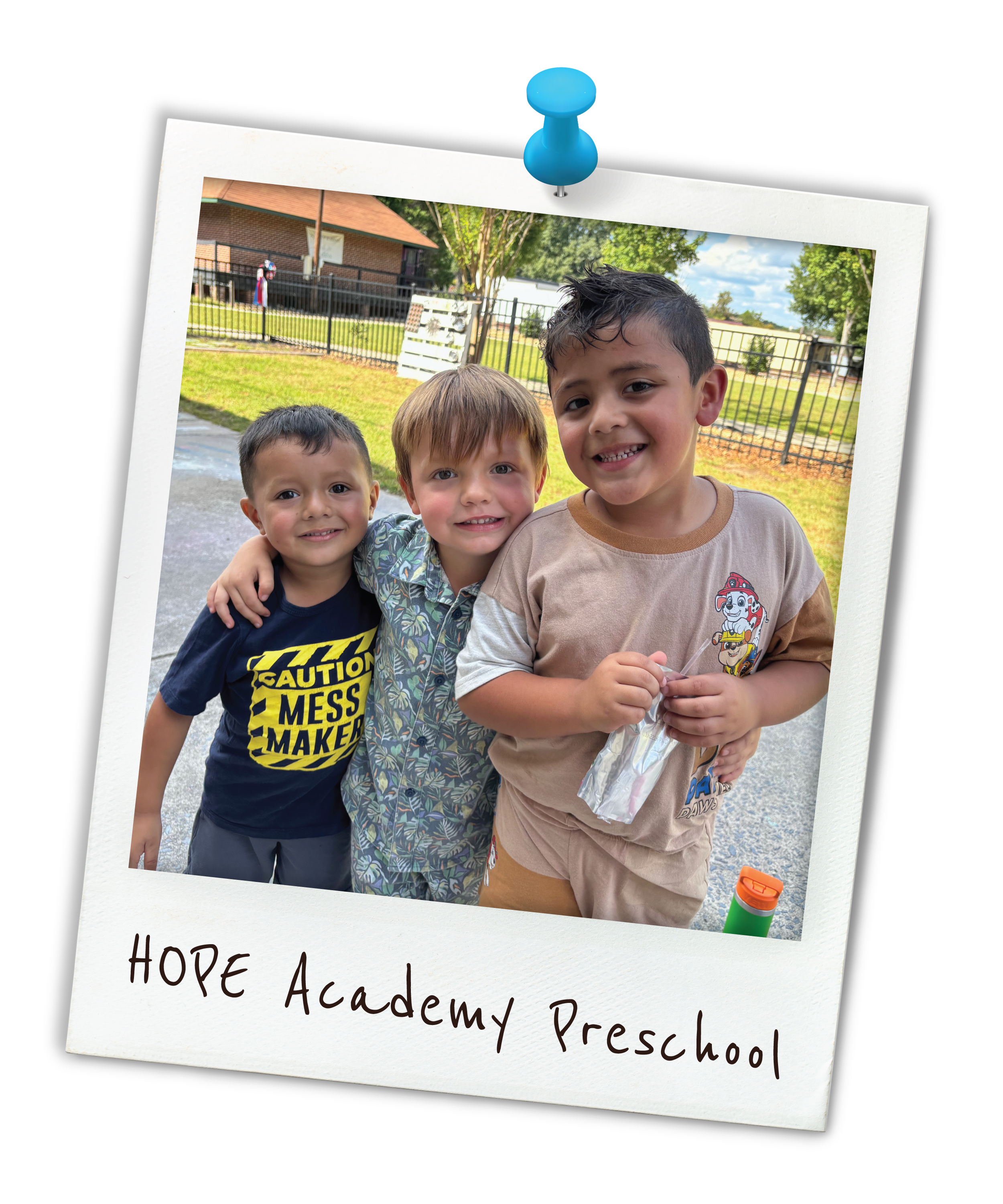 Three young boys smiling and standing together outdoors, with trees, a fence, and a building in the background. One boy is wearing a shirt with a caution message, another has a floral shirt, and the third is holding a plastic bag. The photo is styled as a Polaroid with "HOPE Academy Preschool" written on it.