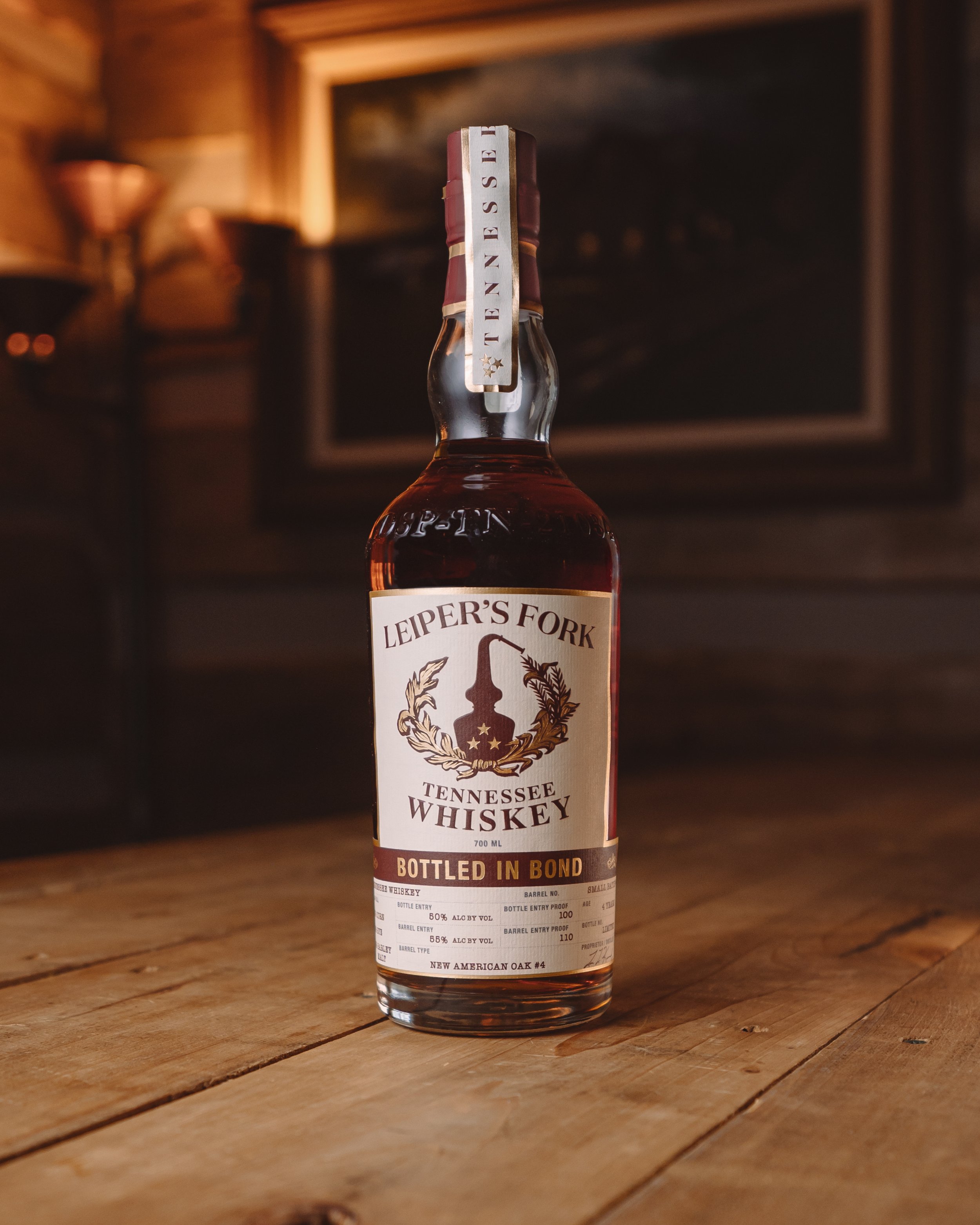 A bottle of Leiper's Fork Tennessee Whiskey on a wooden surface with a rustic background.