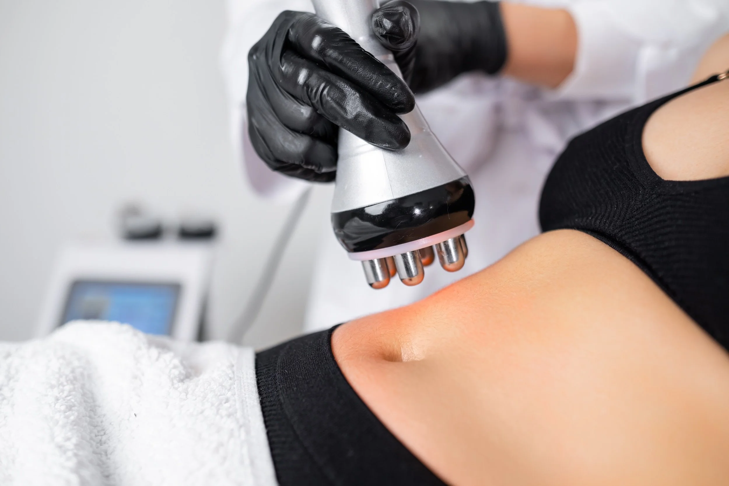 Vacuum radio frequency lifting procedure to reduce fat in belly to young woman in a beauty salon