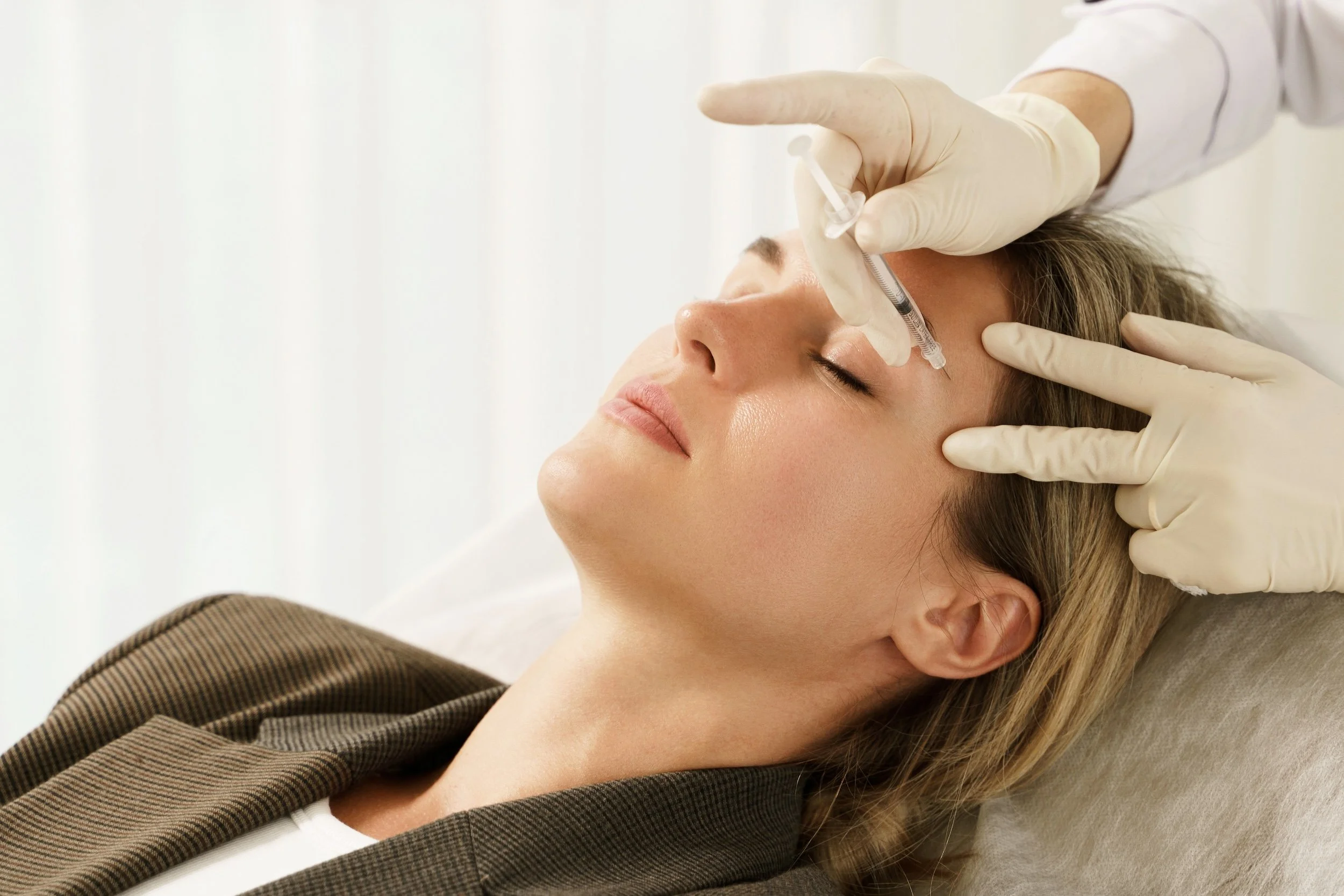 Woman during facial filler injections in aesthetic medical clinic