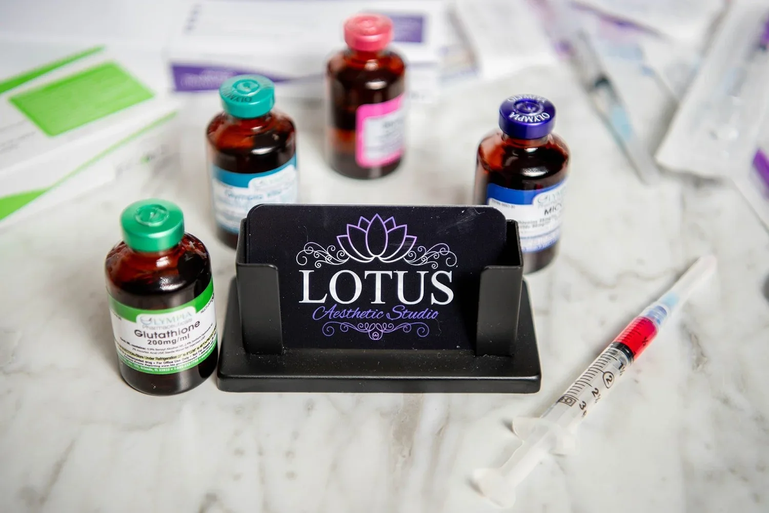 Branding for Lotus Aesthetic Studio shown with clinical supplies including injectable vials for treatments like Glutathione.