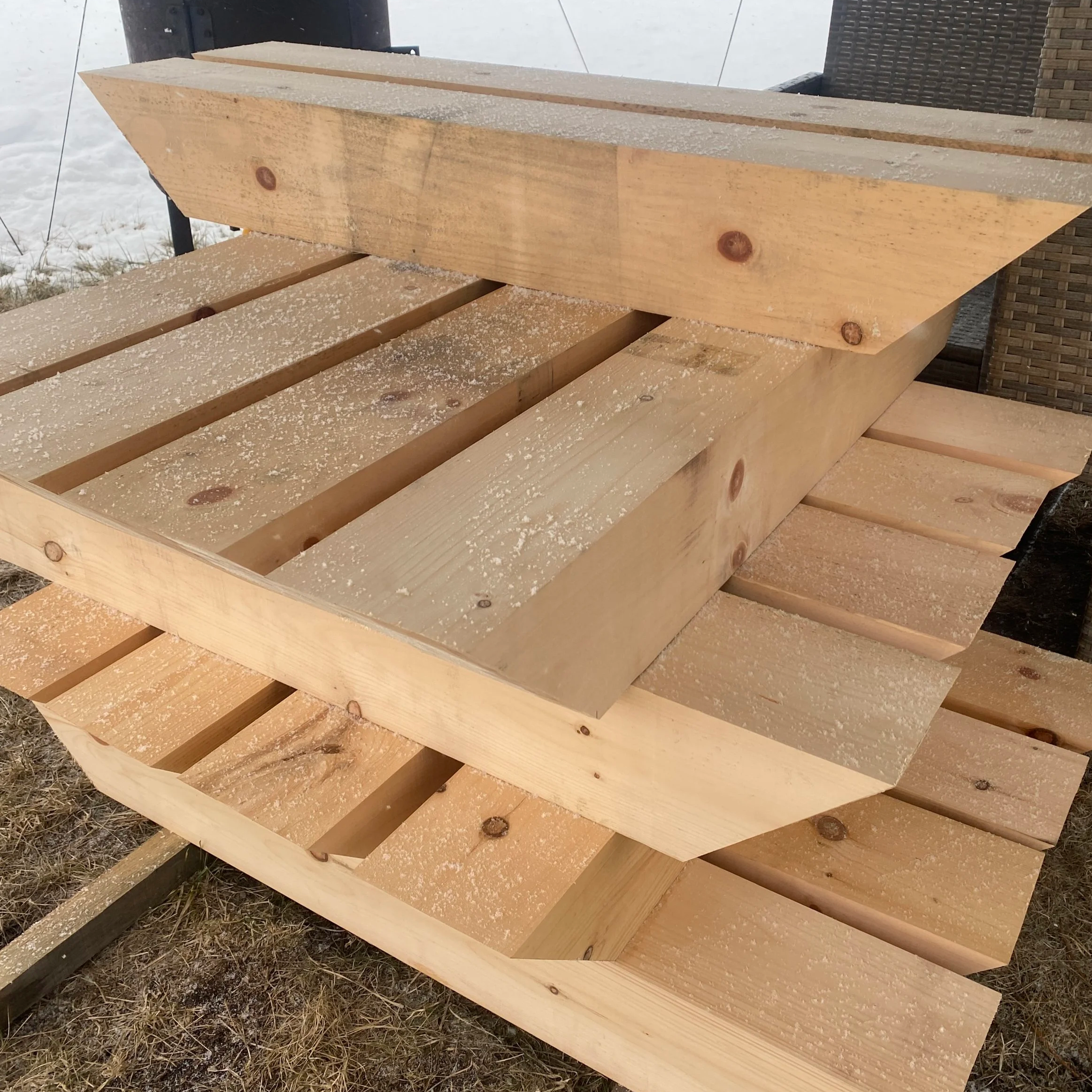Stack of wooden pallets outdoors with snow dusting on the surface.