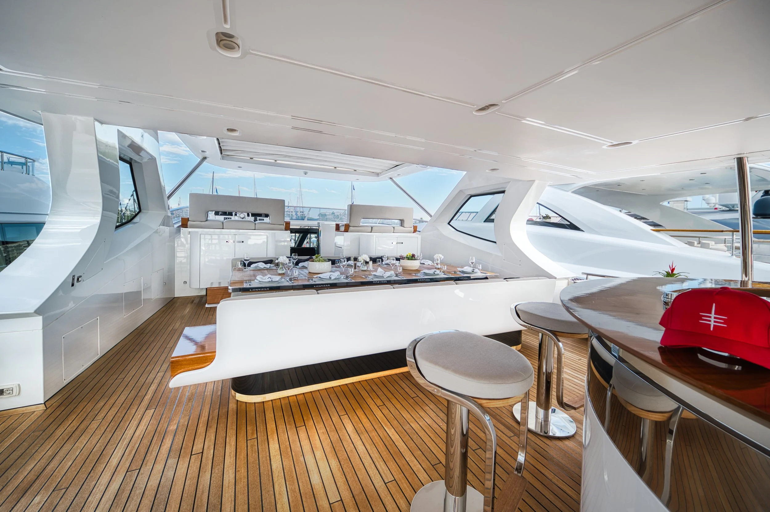 Intérieur d'un yacht avec une table de repas, sièges blancs, décor contemporain et vue sur la marina à travers les fenêtres.