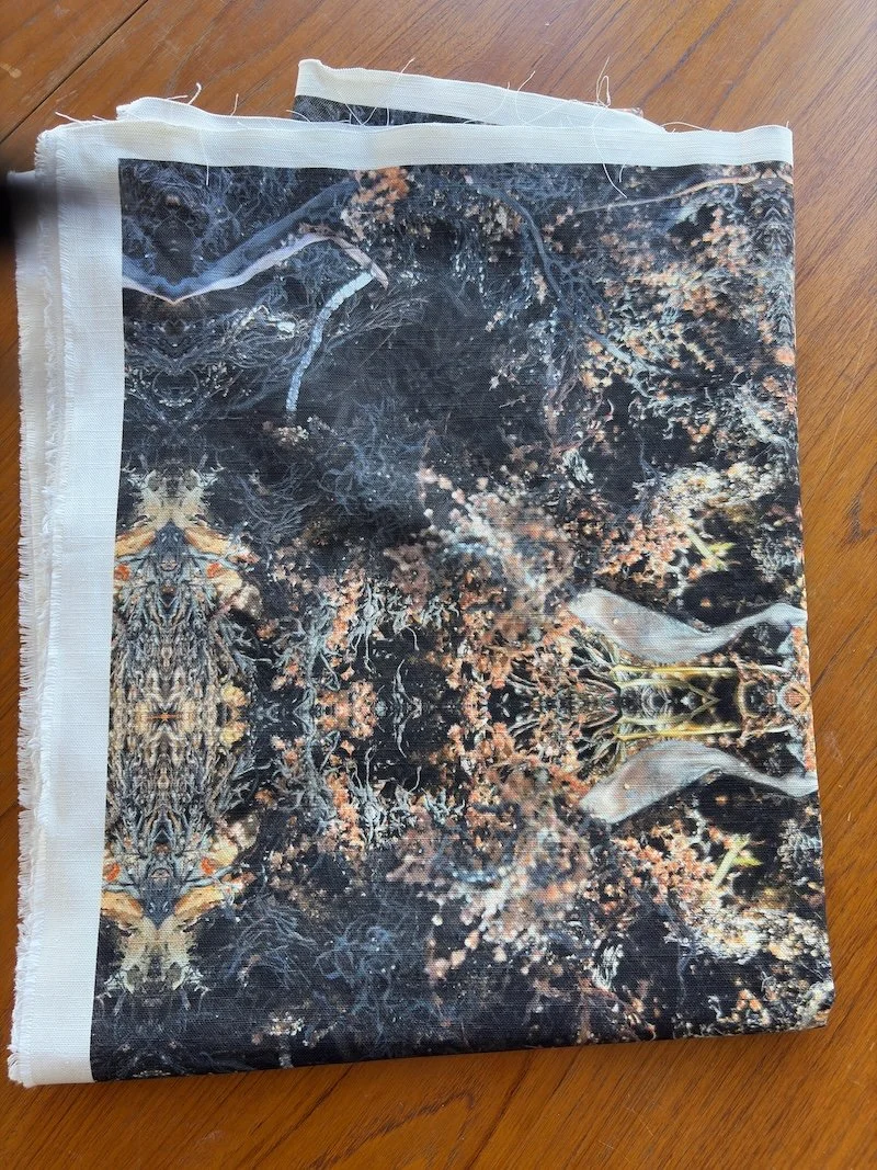 Deep Current fabric folded, in dark charcoal and warm bronze tones showing seaweed and seagrass.