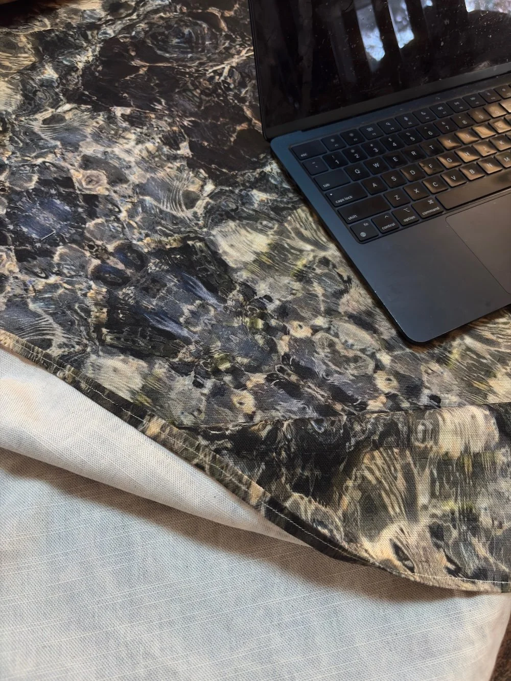Blue Diamond cotton linen fabric folded alongside a laptop, showing the reverse linen ground and pattern face.