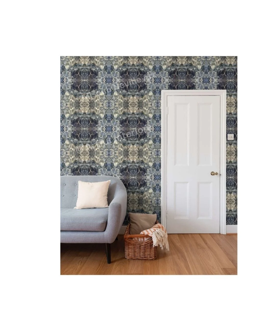 Blue Diamond wallpaper repeat by Artful Weave in a living room — abstract ocean forms in blue, grey-green and cream covering the full wall behind a grey sofa and white door.