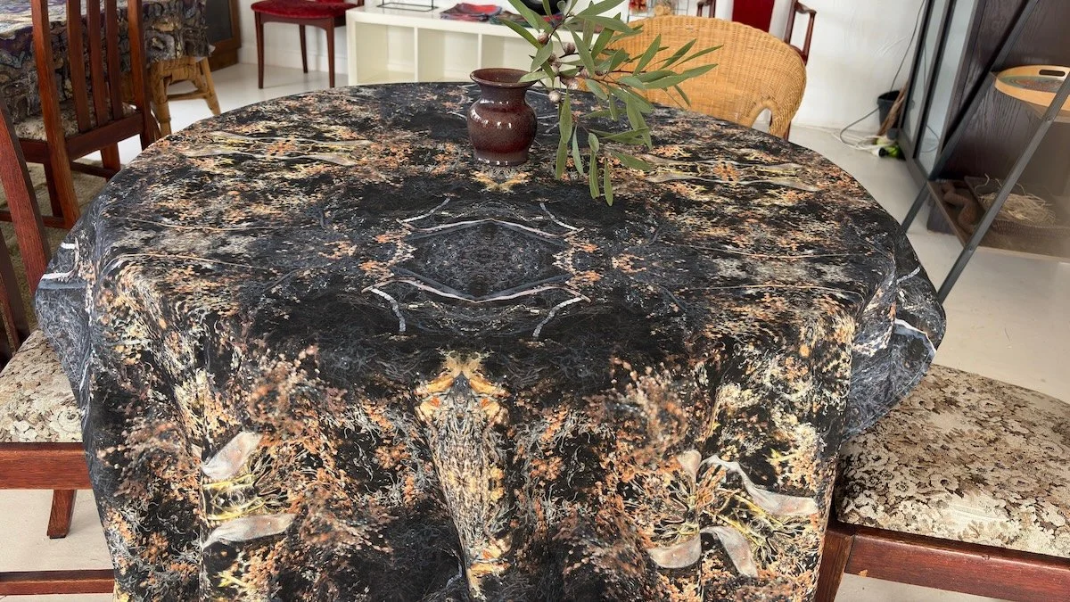 Deep Current fabric and wallpaper design on a cotton linen tablecloth by Artful Weave — a structured yet organic repeat in deep charcoal, bronze and gold tones featuring coastal seaweed and seagrass