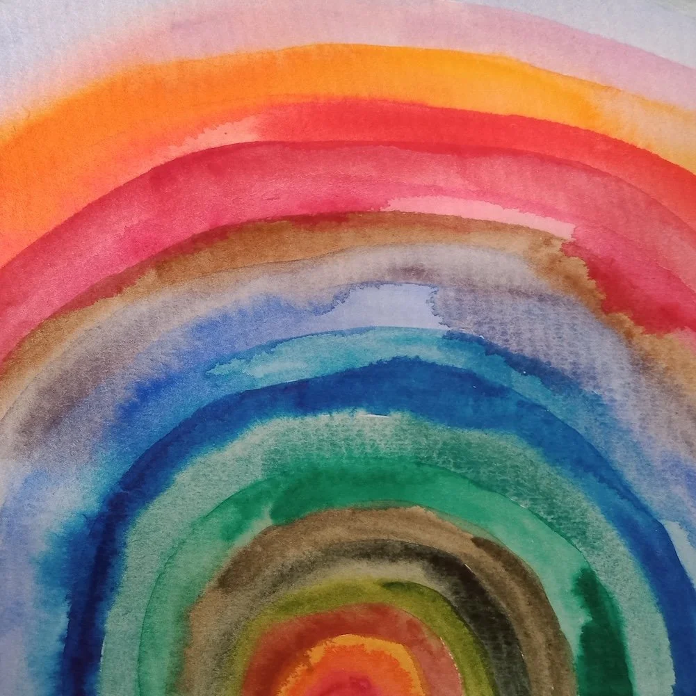 Watercolor painting of a multicolored rainbow with blending colors including red, orange, yellow, green, blue, and purple.