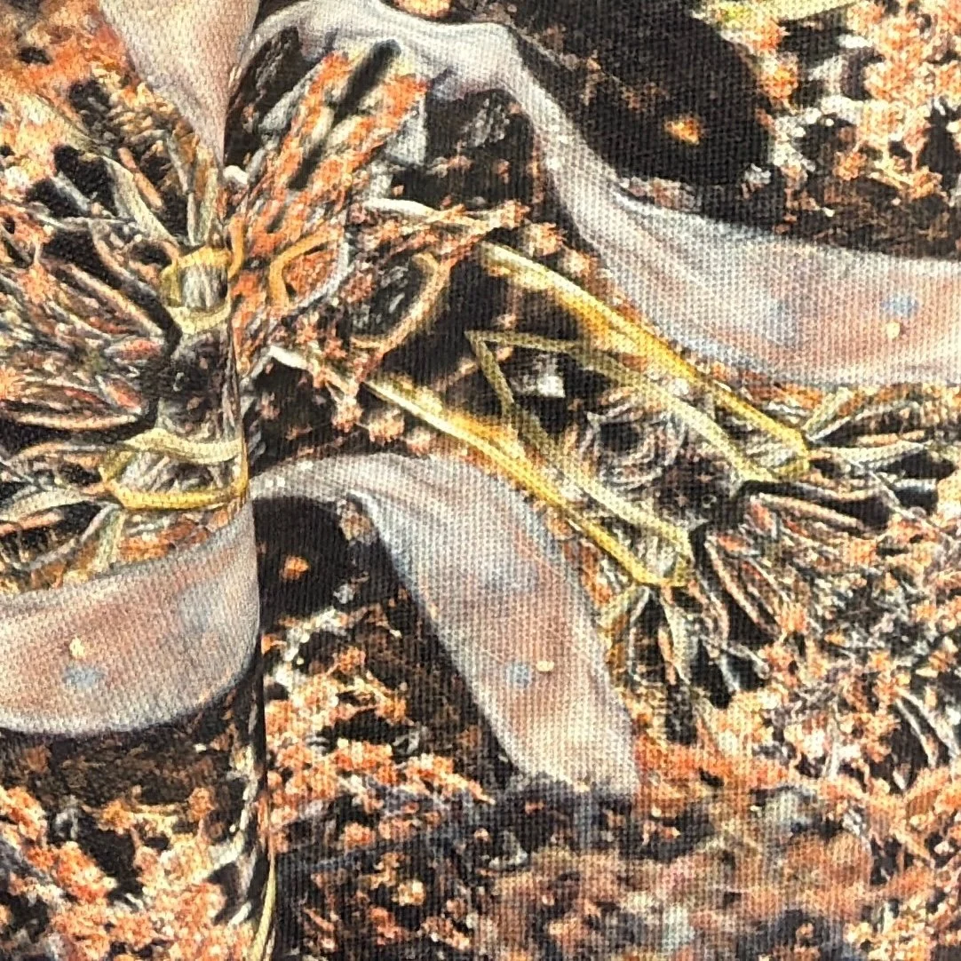 Close detail of Deep Current fabric showing seaweed and seagrass in deep charcoal, bronze and gold.