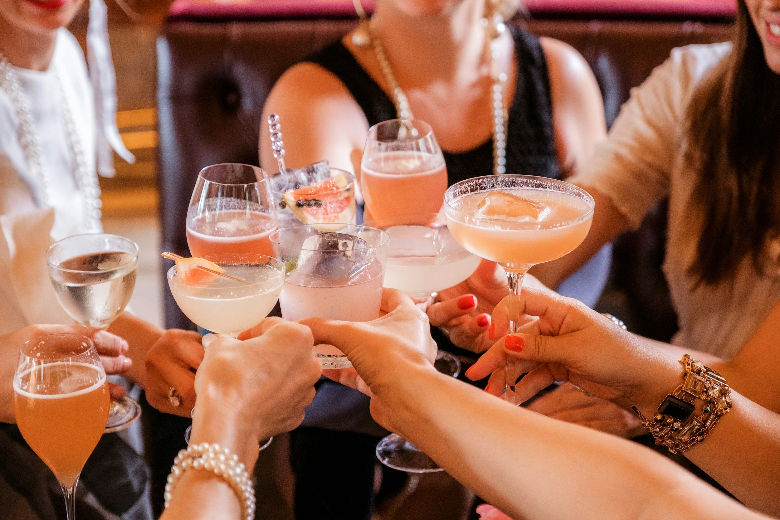 Group of women raising cocktails in a toast at a celebration or social gathering.