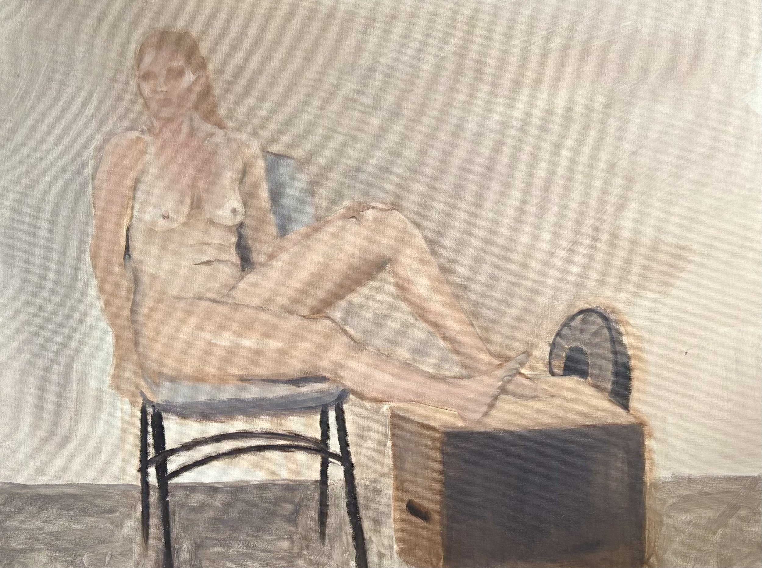 A nude woman with glasses sitting on a chair with her leg resting on a wooden box with a fan inside.