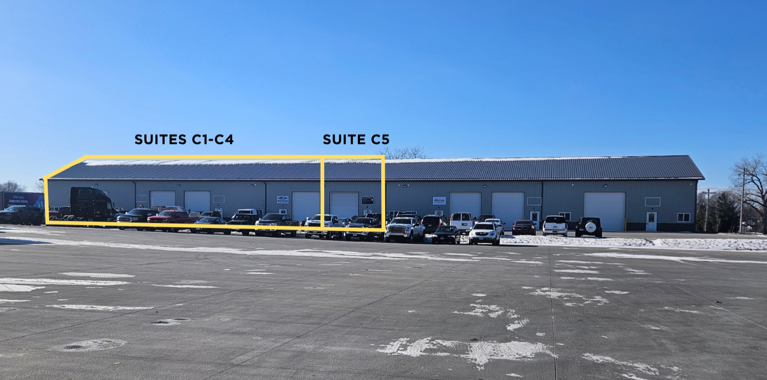 Large industrial building with multiple loading docks, parking lot in front, and clear blue sky. Sections labeled 'Suites C1-C4' and 'Suite C5'.
