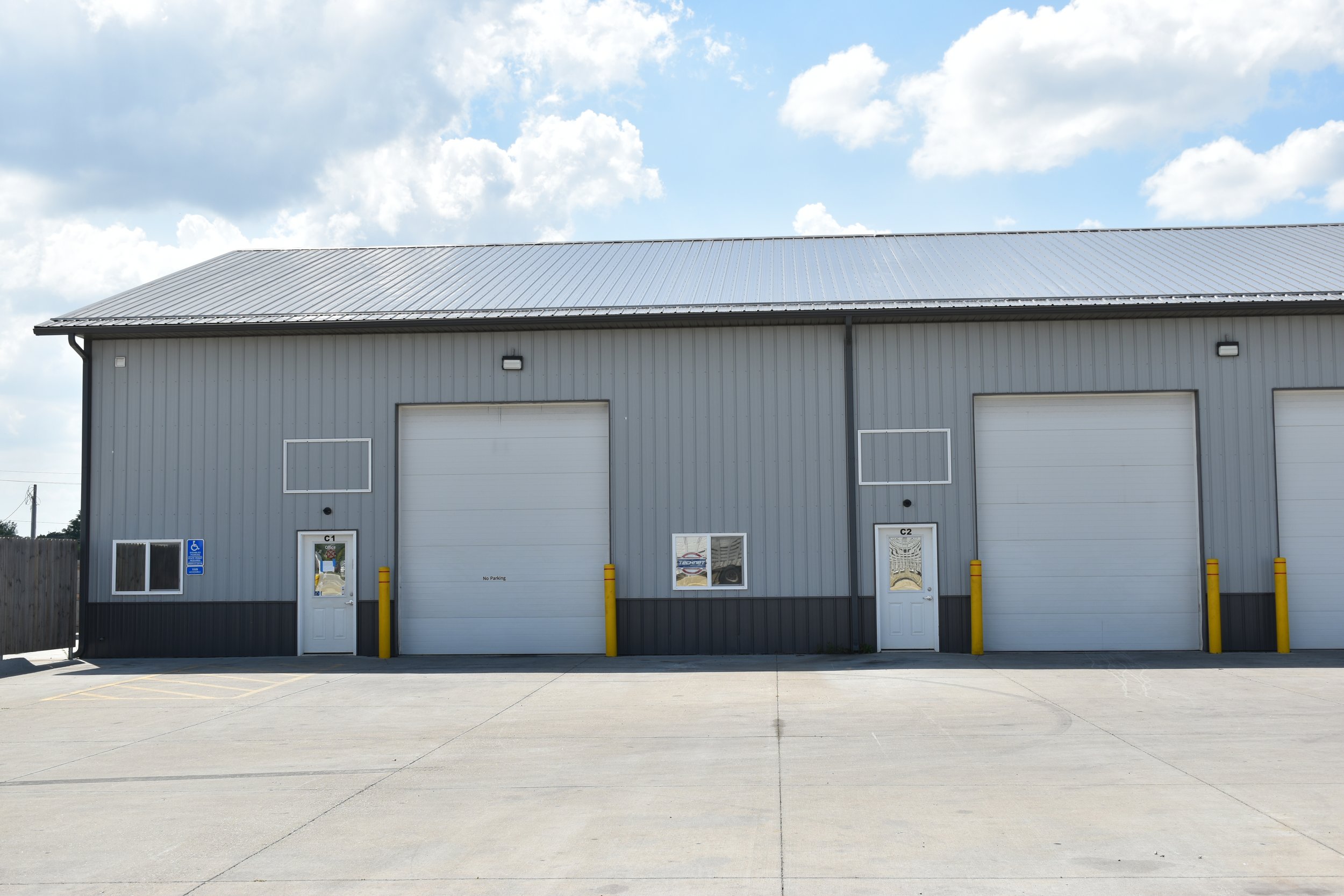 Large industrial building with multiple loading docks, parking lot in front, and clear blue sky. Sections labeled 'Suites C1-C4' and 'Suite C5'.
