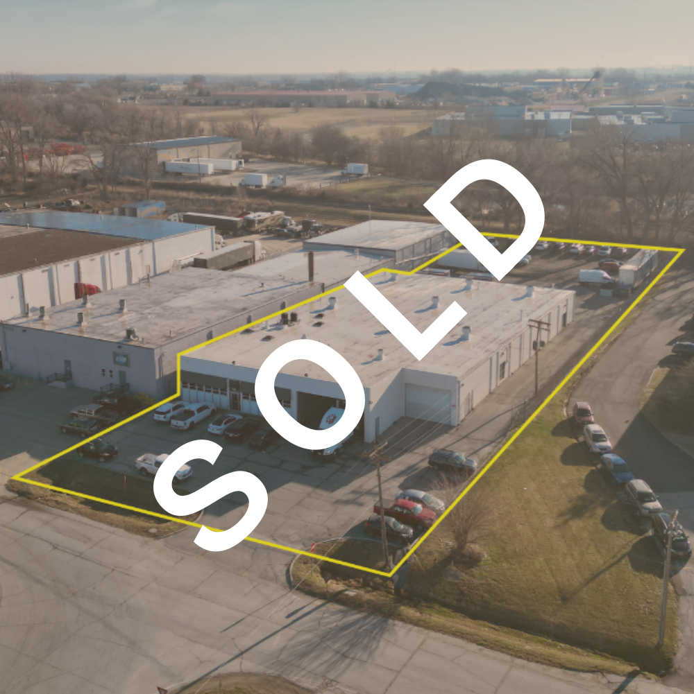 An aerial view of a commercial building with a parking lot, outlined in yellow, and the word 'SOLD' written across the image in large white letters.