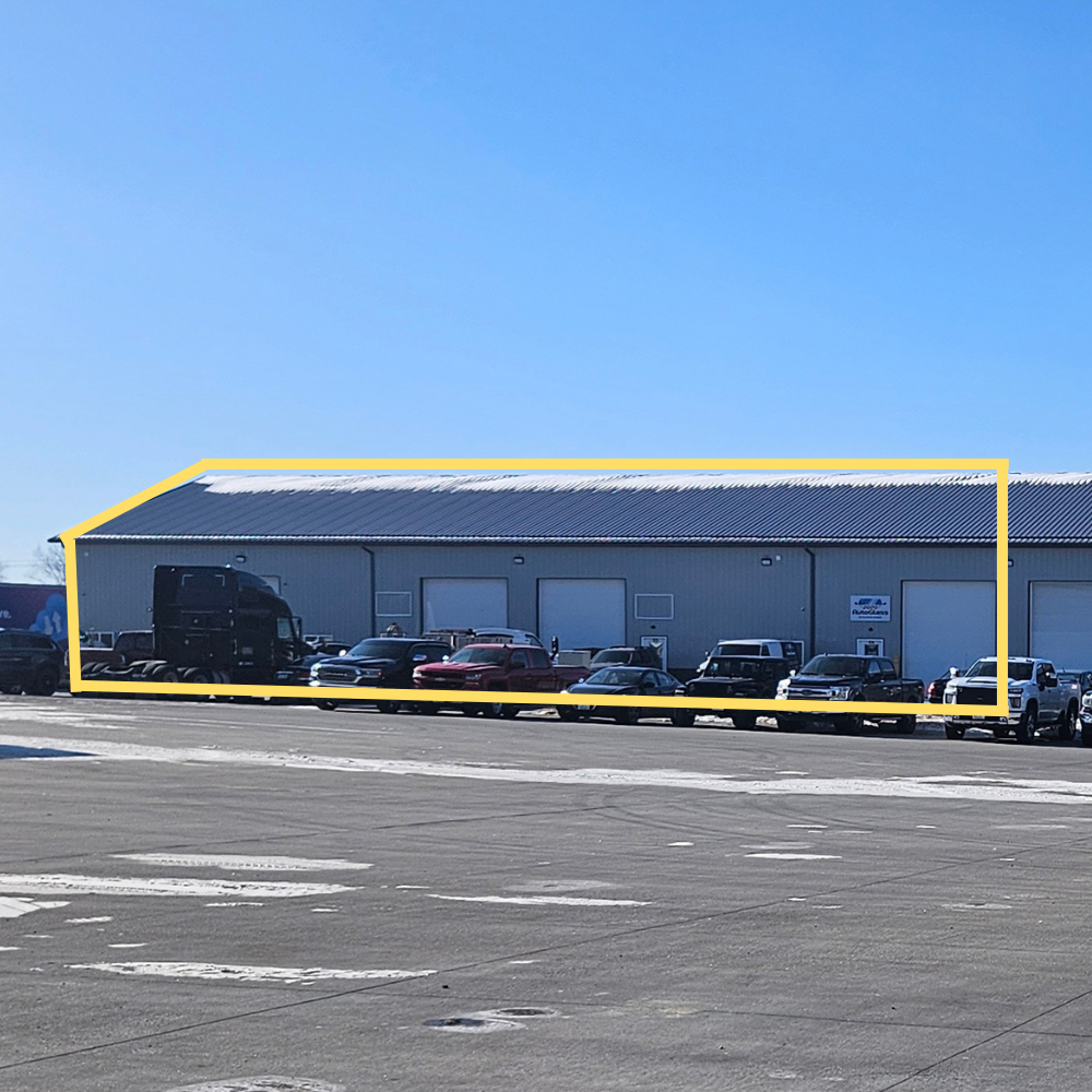 Large industrial building with multiple loading docks, parking lot in front, and clear blue sky. Sections labeled 'Suites C1-C4' and 'Suite C5'.