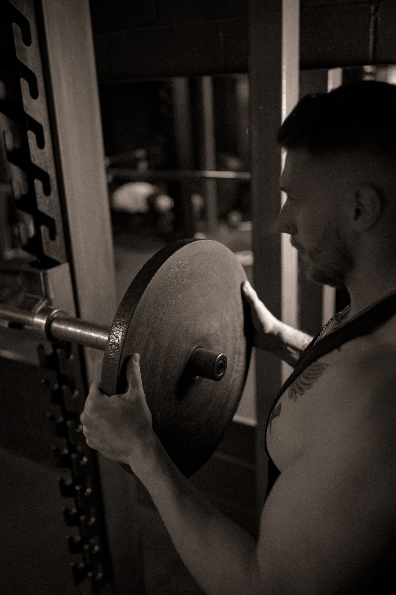 A man lifting a weight plate in a gym.