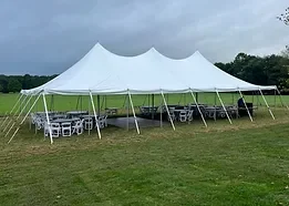 Large white event tent set up outdoors on grass with chairs and tables underneath.