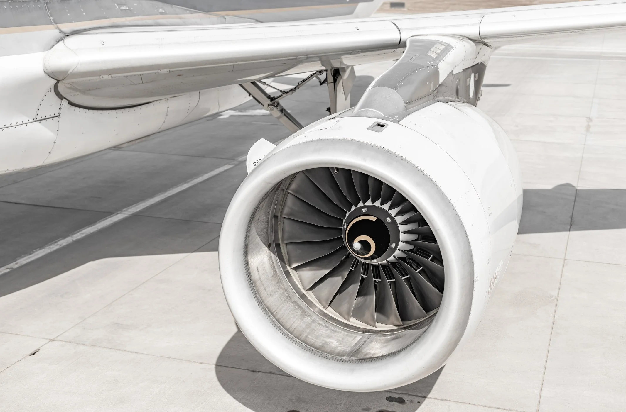 Vista frontal en primer plano de un motor de avión con hélice avanzada y alas blancas en un aeropuerto.