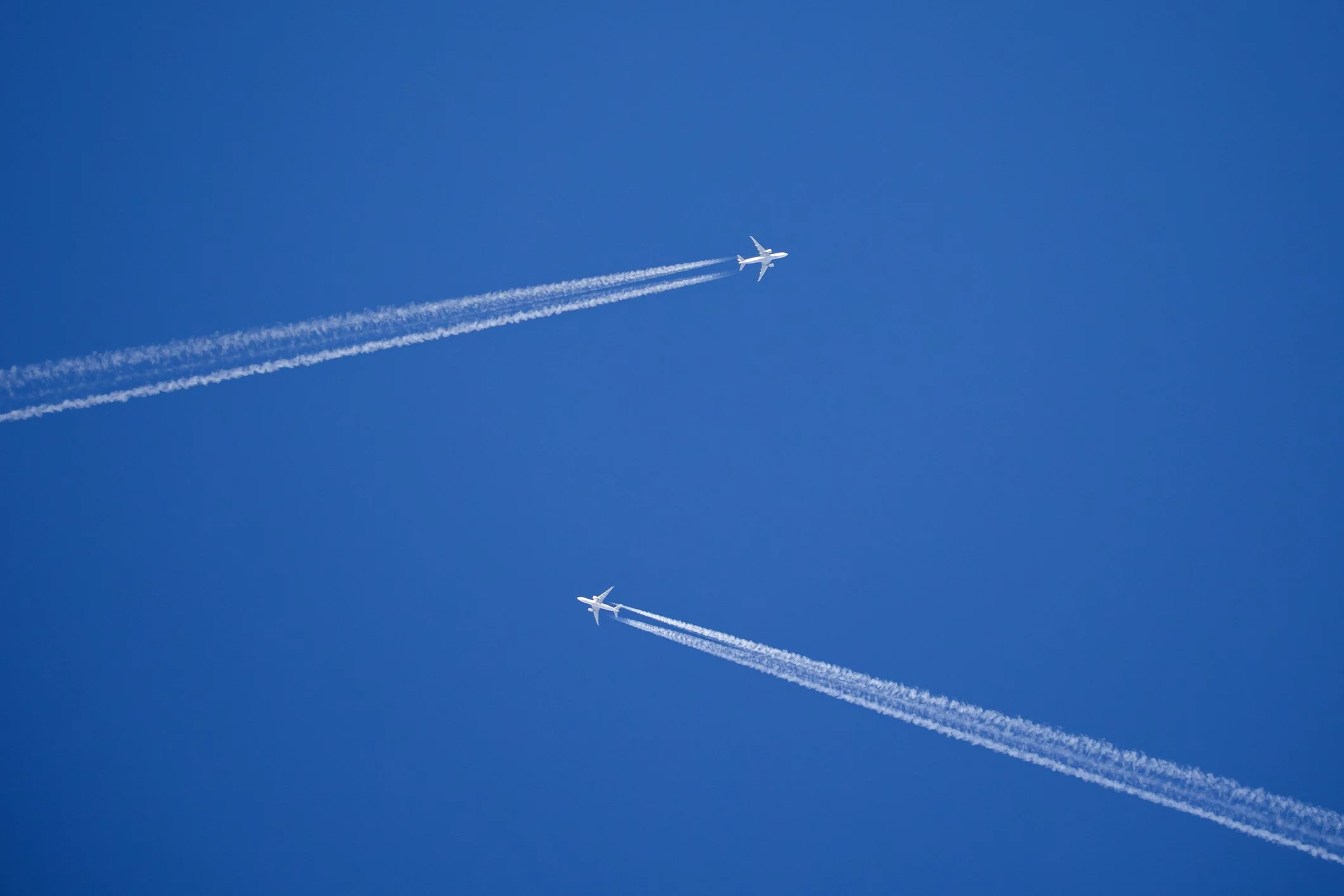 Dos aviones volando en el cielo dejando estelas blancas.
