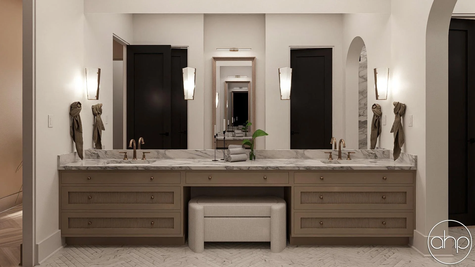 Bathroom vanity with double sinks, marble countertops, beige drawers, upholstered beige stool, and large wall mirror. Four wall sconces and two towel handles on each side of the mirror with towels tied in knots.