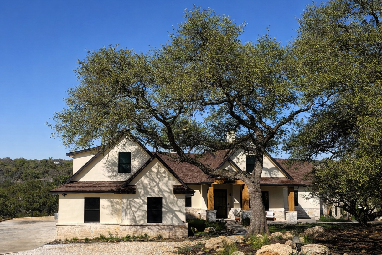 Custom Hill Country home with stone accents, timber columns, and mature oak trees.