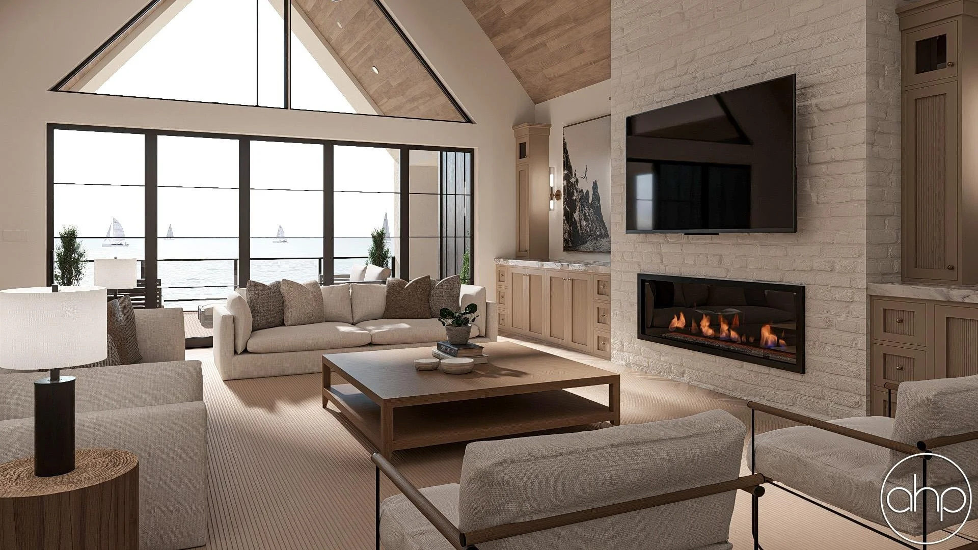 Living room with large triangular window, beige sofas, a coffee table, fireplace, and a wall-mounted TV, with ocean view and sailboats outside