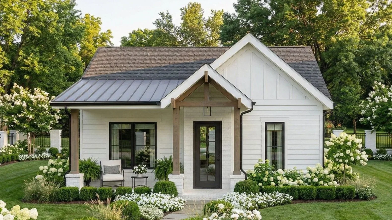 Custom white guest house with a dark metal roof and landscaped front entry.