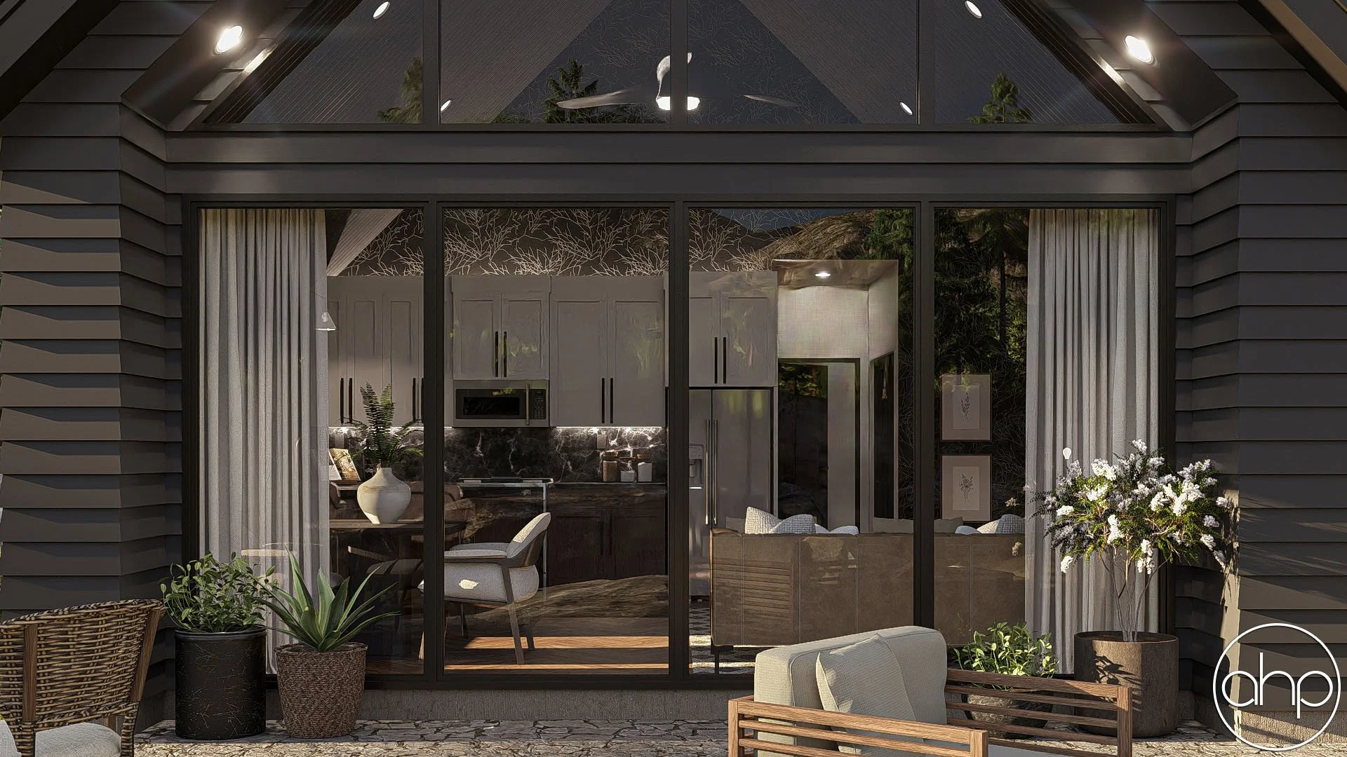 View of a modern house with large glass sliding doors, showing the interior with white cabinets, a refrigerator, and a kitchen area. The outdoor patio has potted plants and furniture. The house has dark siding and a glass roof.
