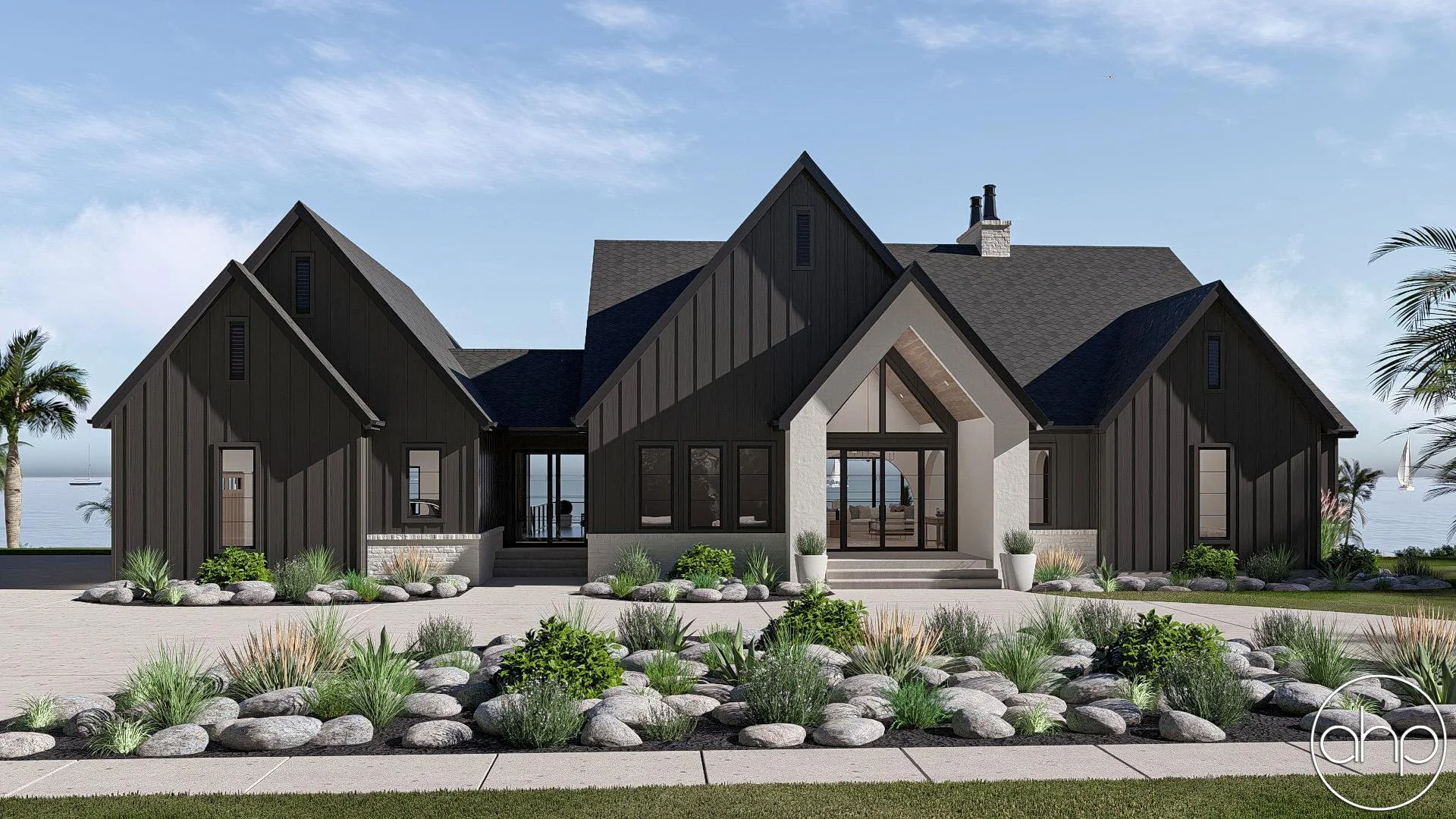 Modern house with black siding and white accents, large front steps, surrounded by rocks and desert plants, near the ocean with sailboats in the background.