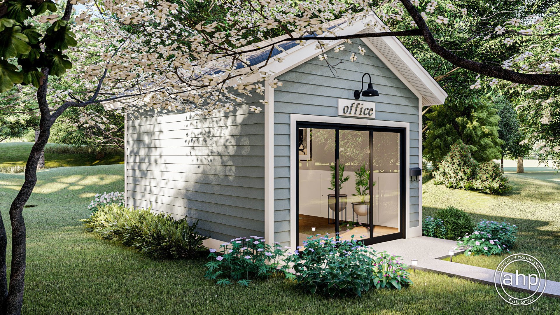 A small, light blue office building with sliding glass doors, located in a lush green garden with flowering trees and shrubs.