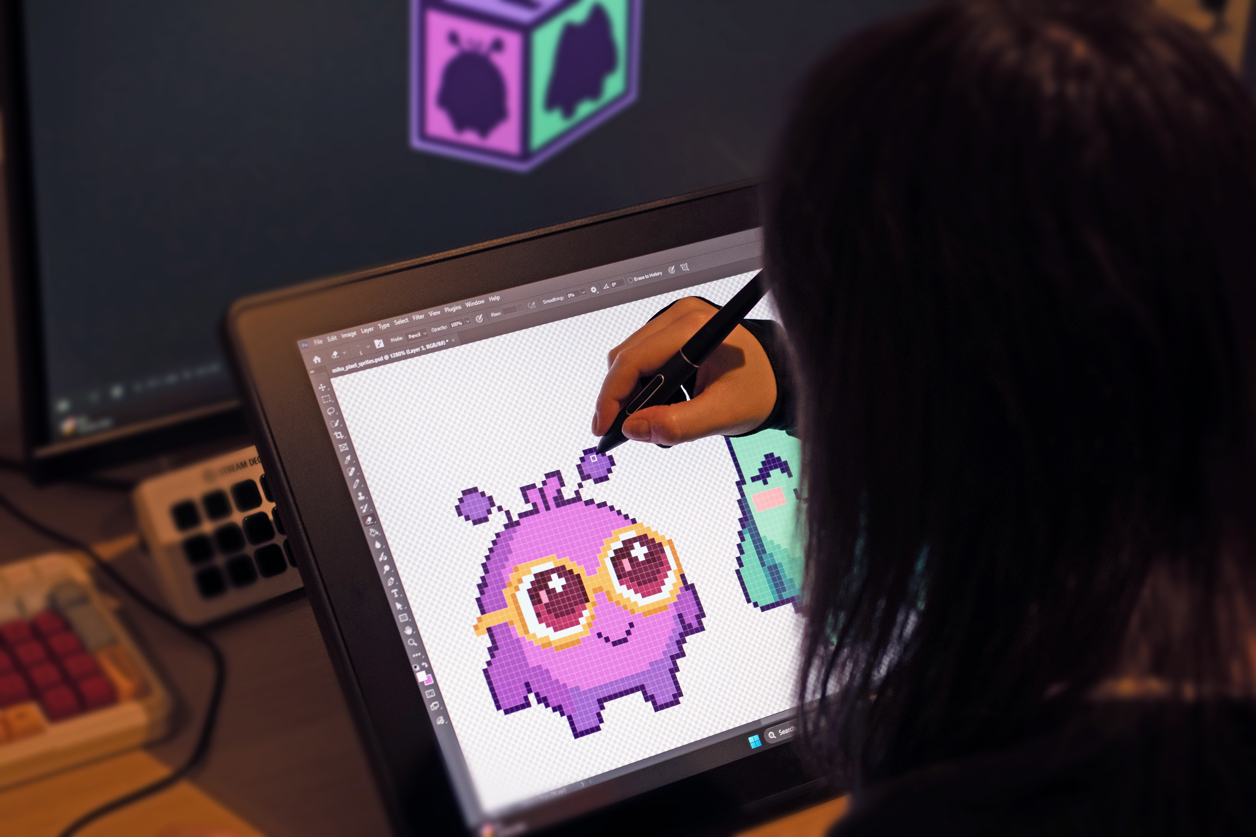 A person working on pixel art of a purple cartoon monster with big eyes and glasses on a digital drawing tablet.