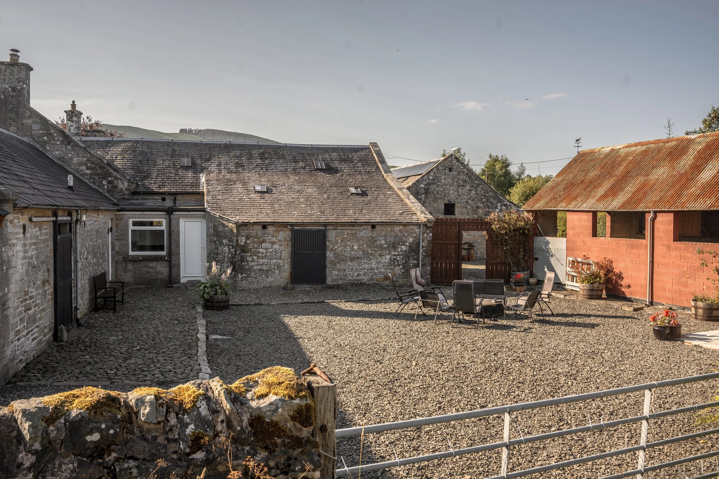 A private courtyard with old stone buildings and a tin-roof barn