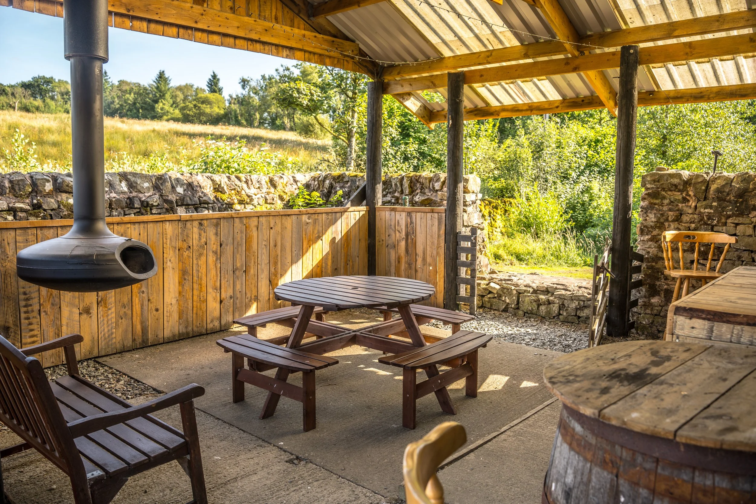 Larriston Coach House undercover seating area with a suspended log-burning fire