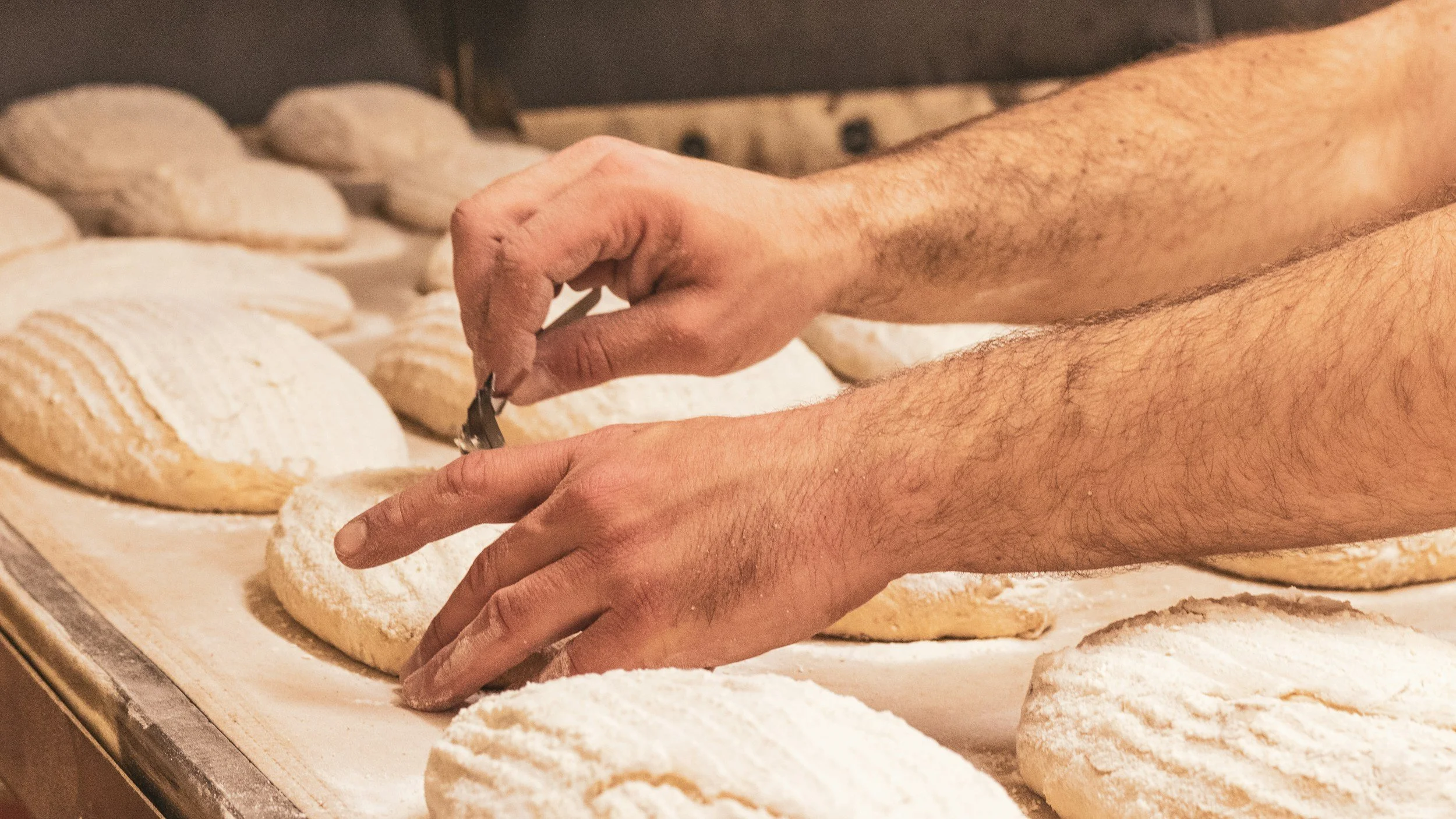 Bäcker scheidet Brotlaibe vor dem Backen ein