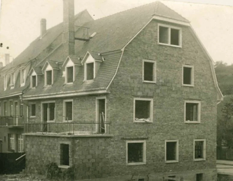 Ein mehrstöckiges Haus im Rohbau mit Ziegelfassade, mehreren Fenstern und einem Balkon.