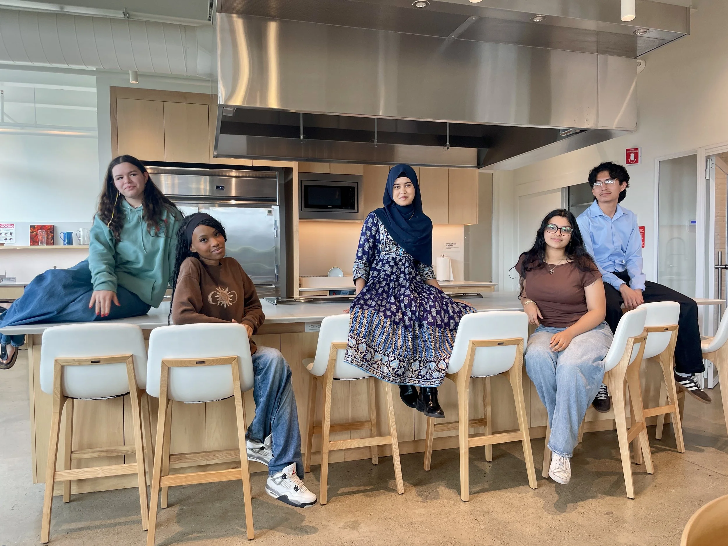 4 young women and one young man sitting on a counter in The Spark of Hudson Kitchen