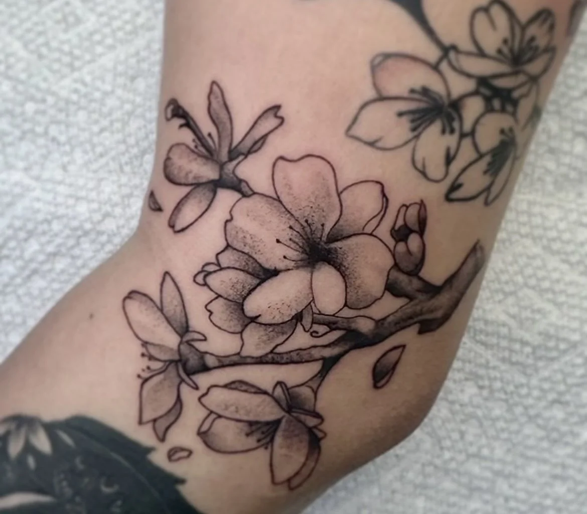Black ink tattoo of blooming cherry blossoms on person's skin. black and grey realism tattoo cherry blossom tattoo fine line tattoo fine line cherry blossom tattoo in Stuart, Sewall’s Point, Hutchinson Island, Jensen Beach, Palm City, Port St. Lucie,