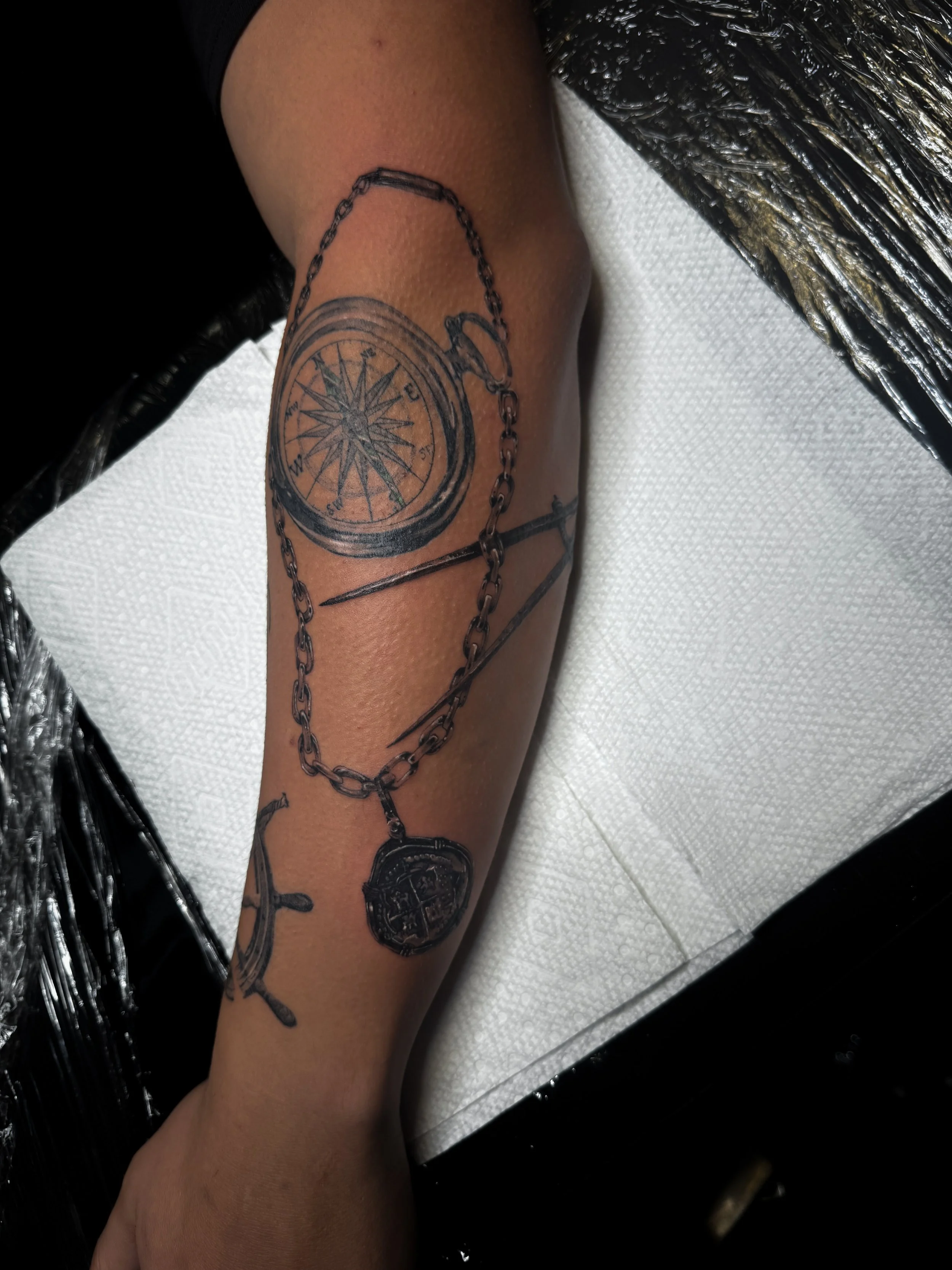 Tattoo of a compass, chain, and skeleton key realism foremarm tattoo tattoo black and grey realism tattoo letterring tattoo, fine line tattoo, in Stuart, Sewall’s Point, Hutchinson Island, Jensen Beach, Palm City, Port St. Lucie, Fort pierce, treasur