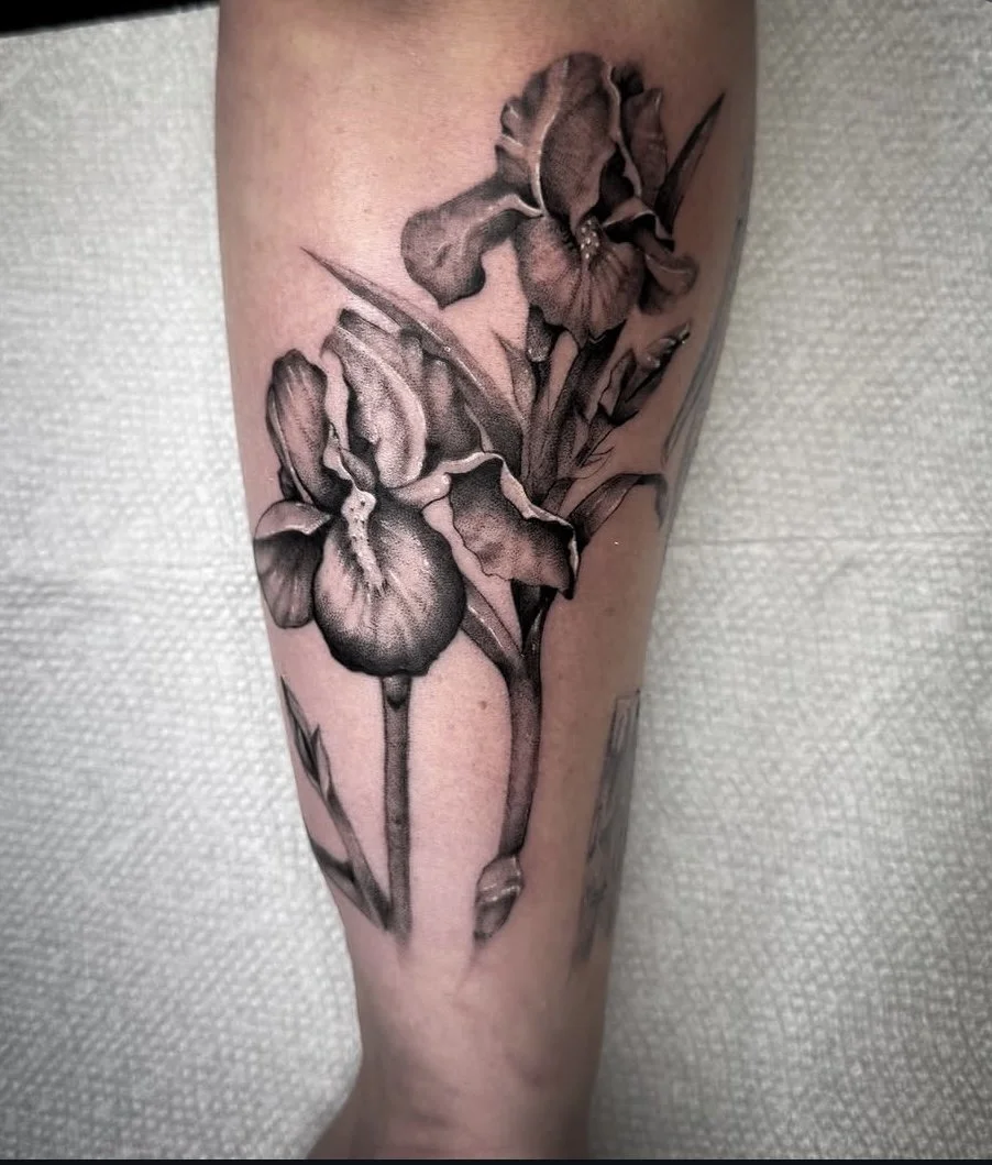 A black and gray tattoo of iris flowers on a person's arm. black and grey realism tattoo iris tattoo in Stuart, Sewall’s Point, Hutchinson Island, Jensen Beach, Palm City, Port St. Lucie, Fort pierce, treasure coast and surrounding South Florida area