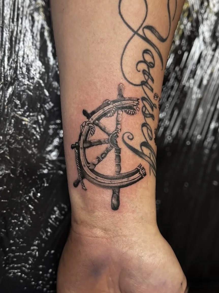 Tattoo of a ship's wheel and a compass on a person's arm, wrist tattoo with cursive script  ship wheel tattoo realism tattoo black and grey realism tattoo letterring tattoo, fine line tattoo, in Stuart, Sewall’s Point, Hutchinson Island, Jensen Beach