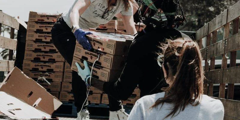 People loading or unloading boxes of Cal-Organic vegetables from a truck bed.