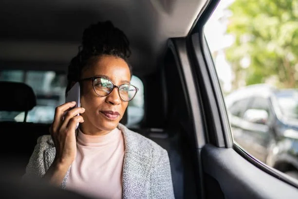 Woman with glasses talking on a cellphone inside a car