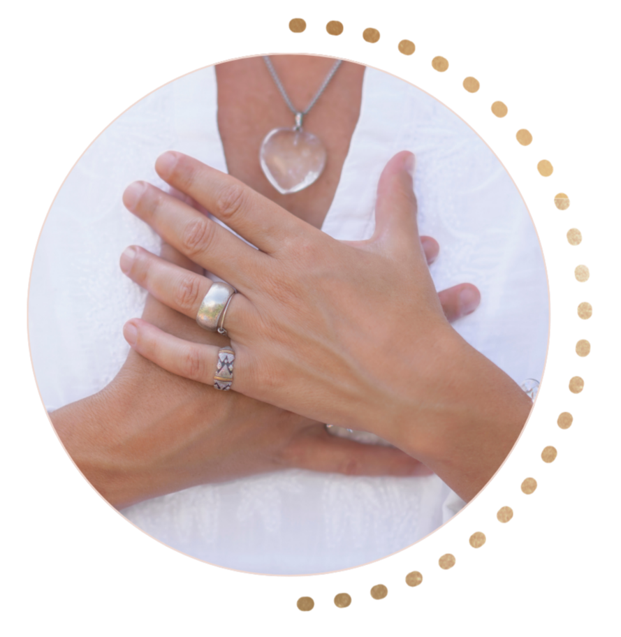 Close-up of a woman's hands with rings and a necklace, resting on a white surface.