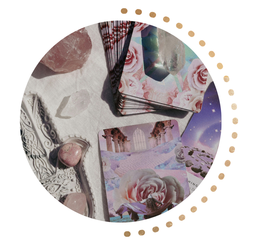 A circular arrangement of tarot or affirmation cards with floral and fantasy themes, placed on a white fabric surface. There are also decorative stones, a white ornate object, and a starry night sky illustration.
