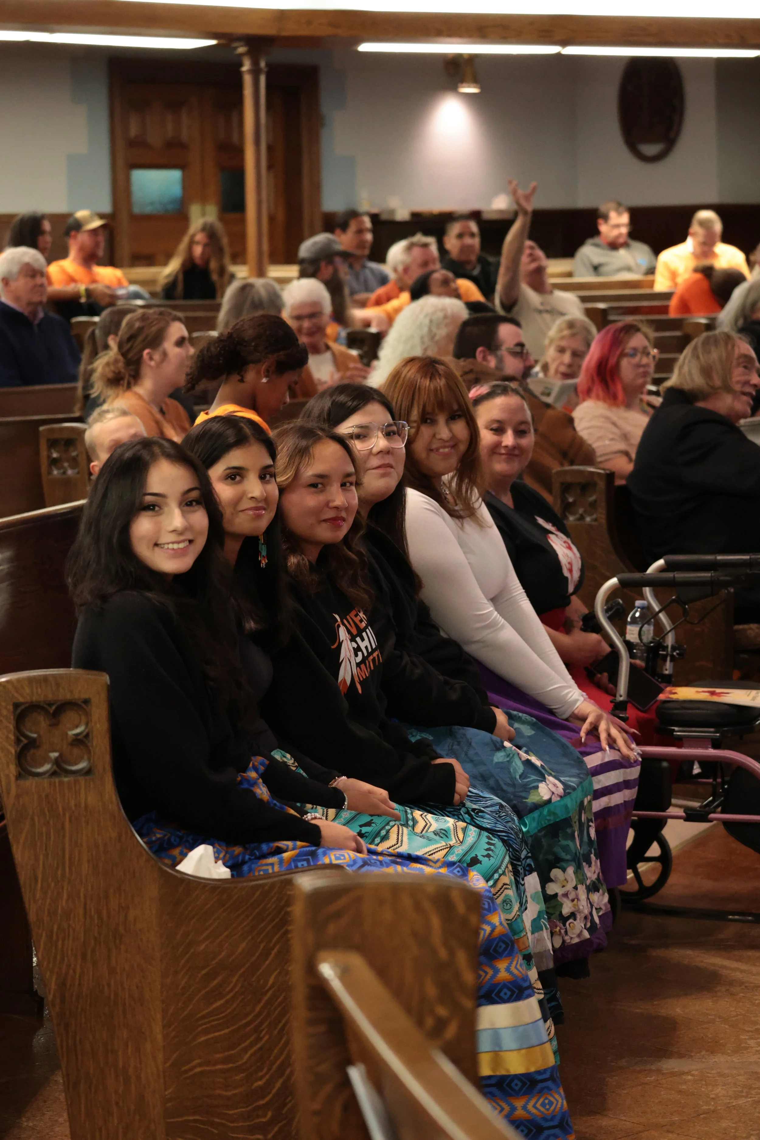 Group of women sitting in pews at a church, attending an event or ceremony.