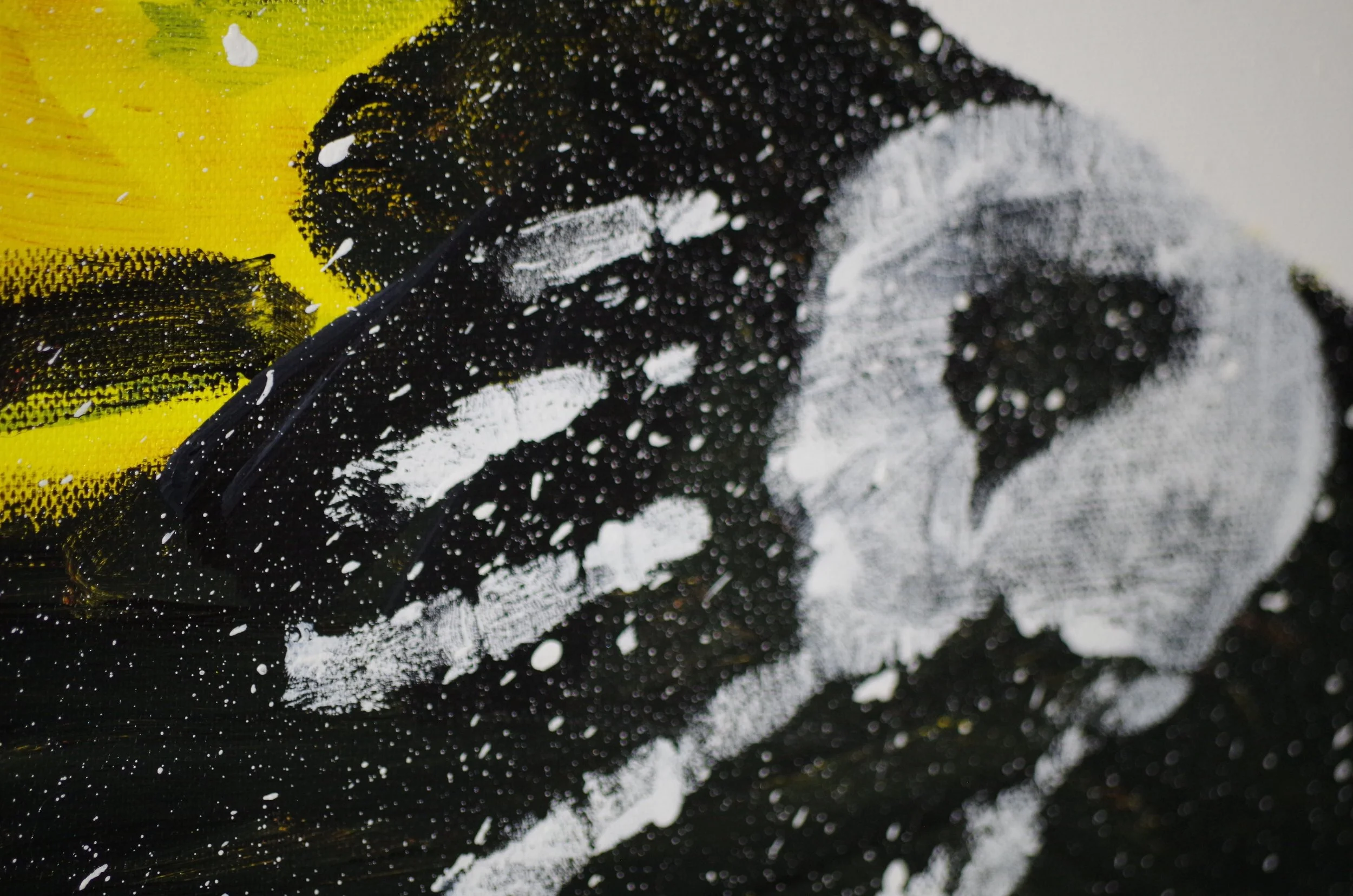 Close-up of a painted or printed black, white, and yellow surface with visible paint splatters and brushstrokes.