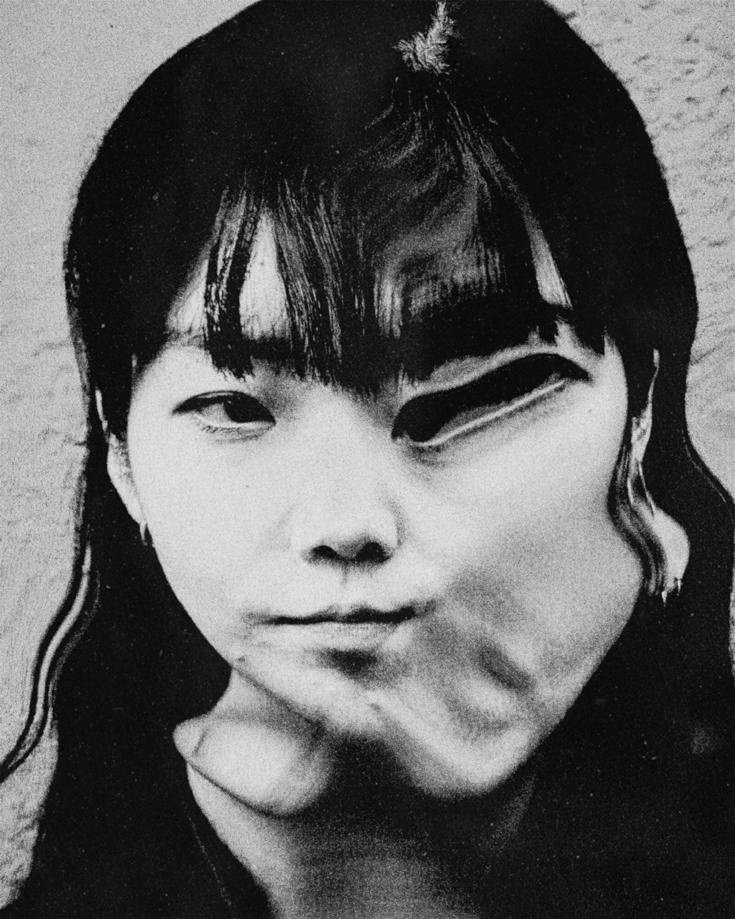 Close-up black and white photo of person's face, focusing on eyes, nose, and mouth, with hair covering parts of the forehead and cheek.