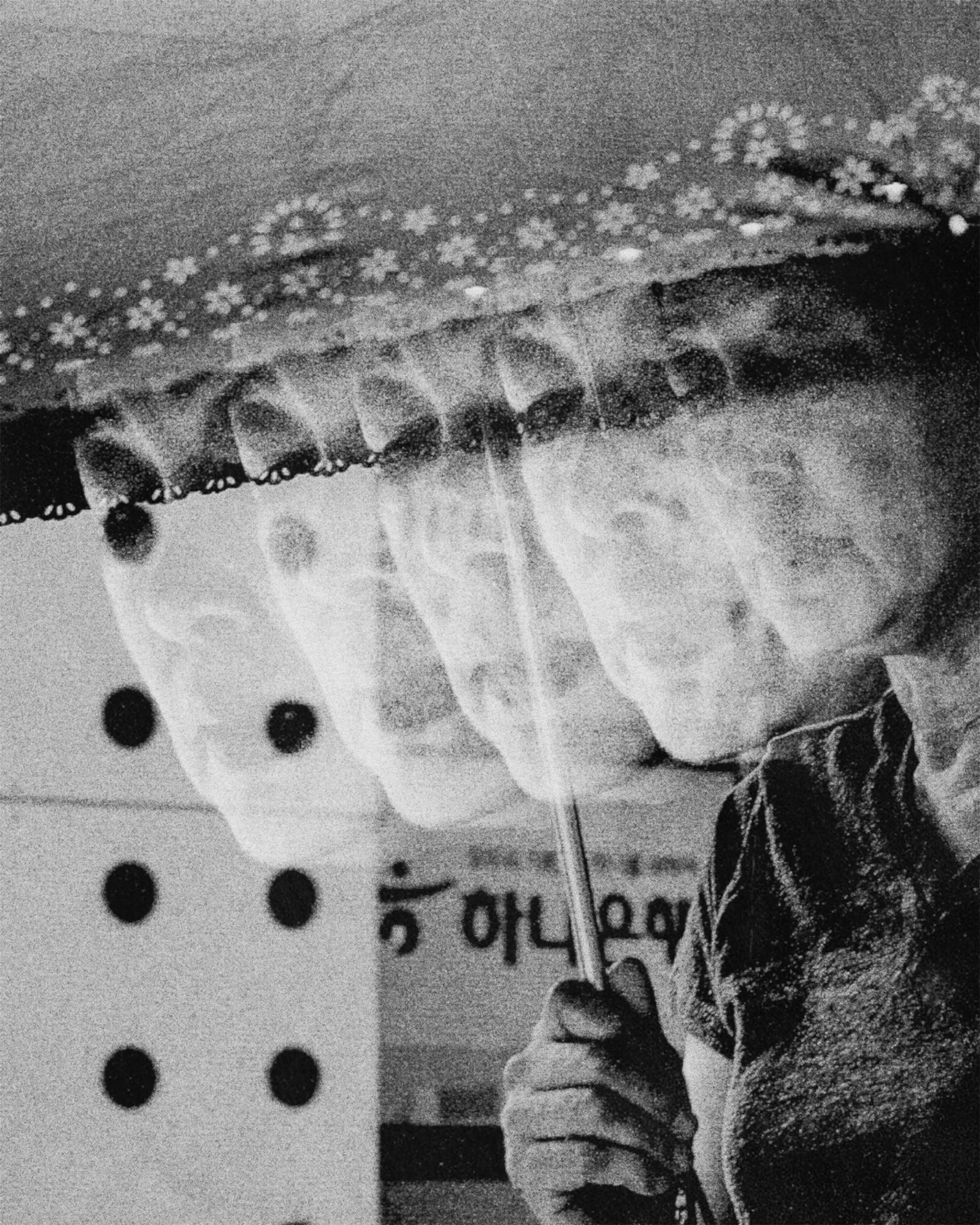 Pointillist style black and white image of a person's face with spectacles, partially obscured, next to a pattern of black dots and unreadable text.